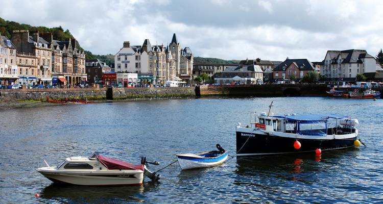 Ville côtière d'Oban avec des bateaux amarrés au premier plan et une architecture victorienne longeant le front de mer.