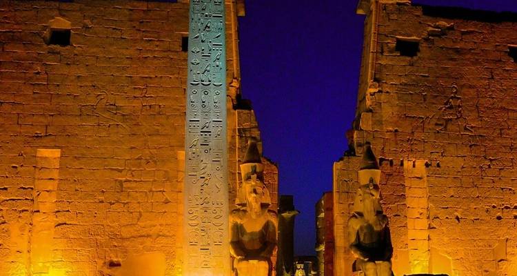 De Luxor Temple verlicht in goudgeel licht steekt prachtig af tegen een diep indigoblauw nachtelijke hemel.