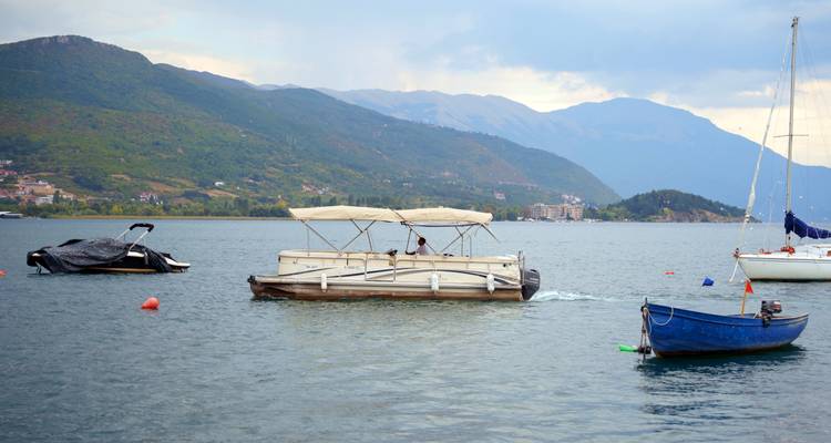 De petits bateaux amarrés sur un lac tranquille entouré de pentes verdoyantes et montagneuses.