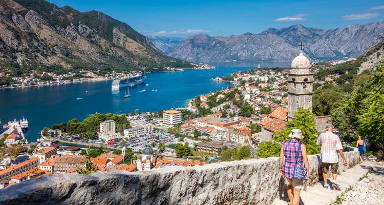 Les randonneurs descendent un sentier en pierre au-dessus de la baie de Kotor avec un navire de croisière et des montagnes en vue.