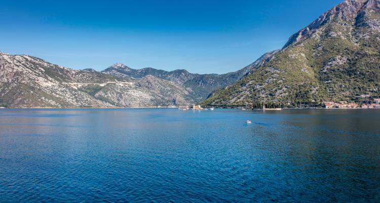 Vaste étendue tranquille de la baie de Kotor entourée par des montagnes calcaires escarpées.