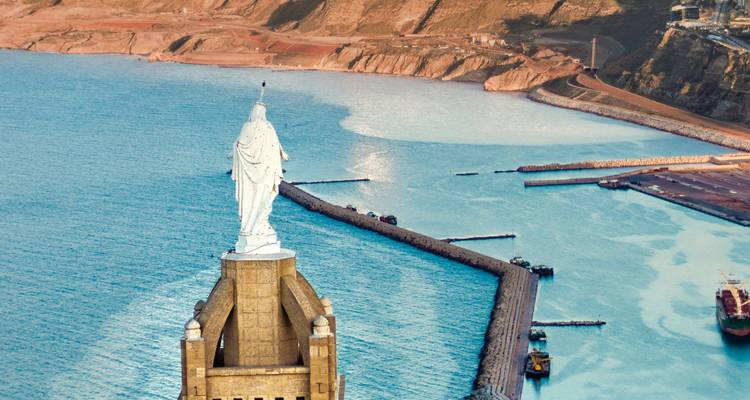 Gros plan de la statue de Santa Cruz au sommet de la colline surplombant la mer Méditerranée et le port.