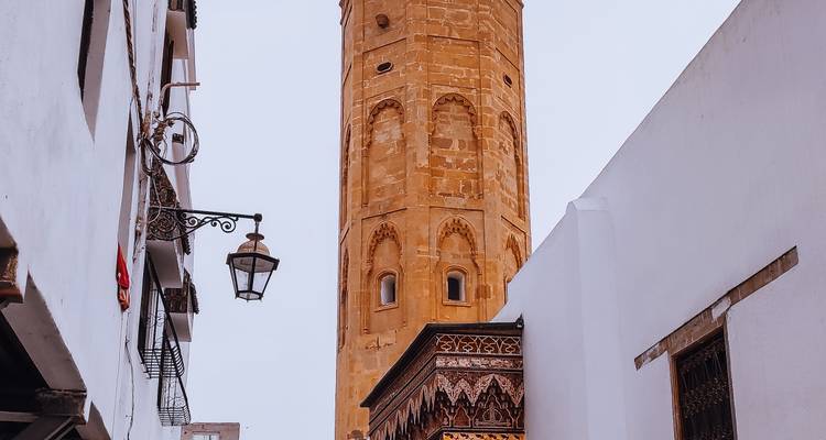 Un haut minaret de pierre s'élève au-dessus de ruelles étroites aux murs blanchis à la chaux.