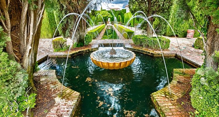 Les jardins de la Generalife avec leurs fontaines symétriques et leurs haies luxuriantes, ornés de jets d'eau en arc.