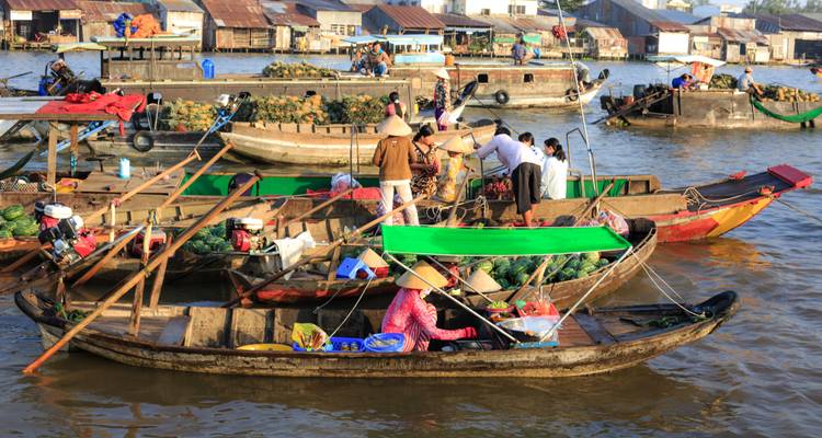 Bustling floating market with produce-laden wooden boats trading on a broad brown river.