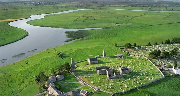 Vue aérienne des ruines monastiques de Clonmacnoise situées dans de vastes champs verdoyants le long du fleuve Shannon.