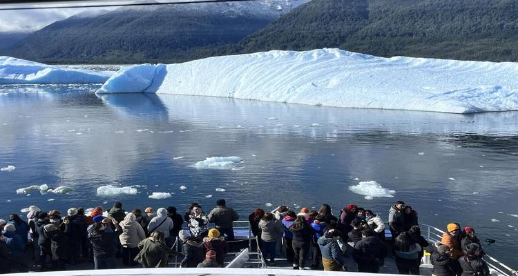 Cruise passengers crowd the bow to view huge floating icebergs in a glacier lagoon.