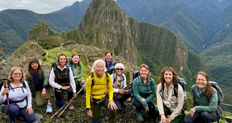 Groupe de femmes souriantes posant sur un belvédère surplombant les terrasses emblématiques et le pic de Machu Picchu