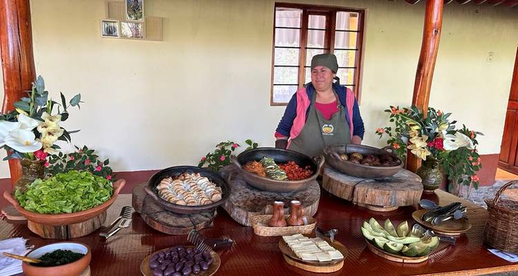 Une femme locale se tient derrière un assortiment rustique de plats traditionnels péruviens dans un espace de restauration convivial.