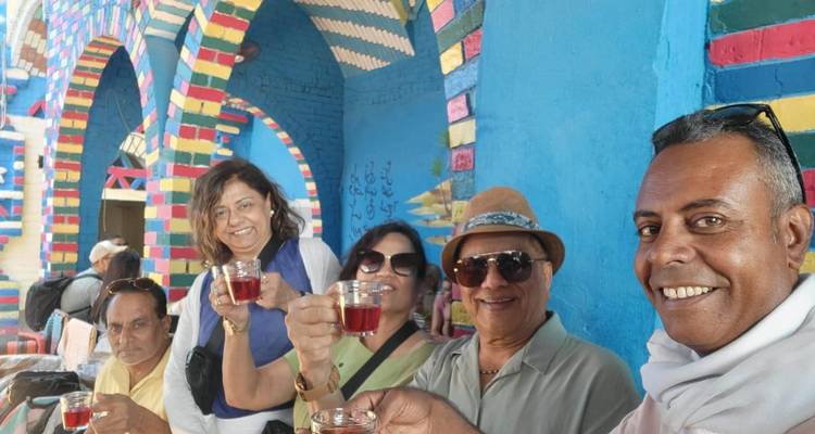 Les voyageurs trinquent avec de petits verres de thé à l'hibiscus dans un café de village nubien aux couleurs éclatantes.