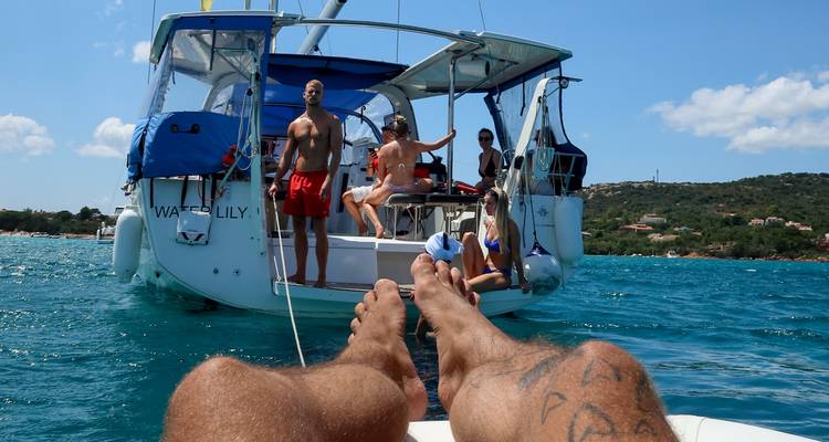 Relaxed view from a catamaran trampoline toward friends on another sailboat anchored in turquoise water