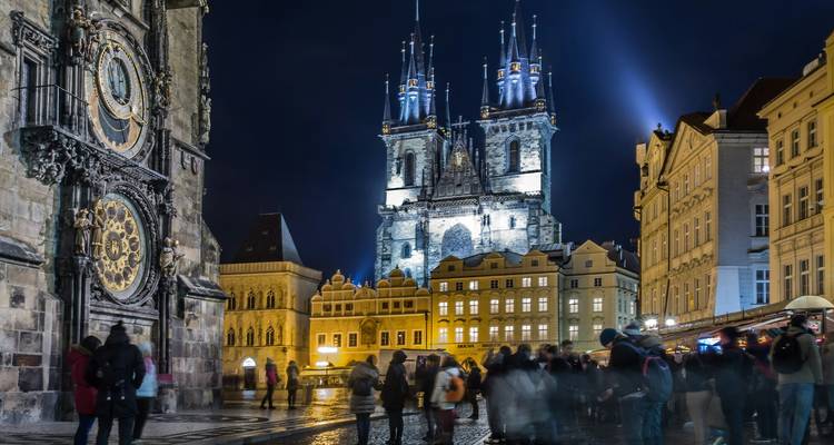 Night scene in Prague’s Old Town Square featuring the Astronomical Clock and illuminated Týn Church.