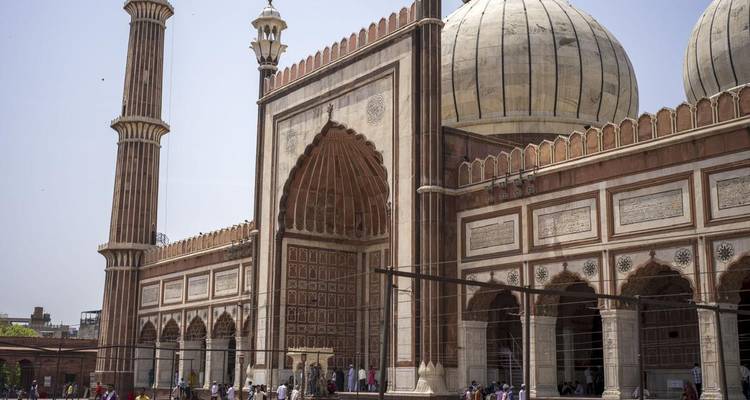 Grand entrance facade of Jama Masjid with visitors milling around vast courtyard.