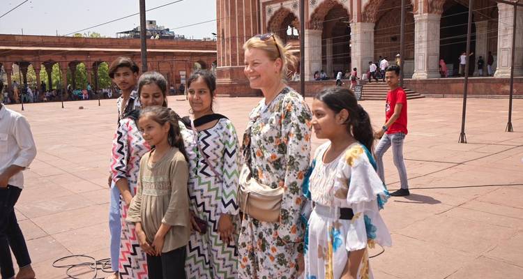 Smiling tourist poses with local girls in patterned dresses outside Jama Masjid.