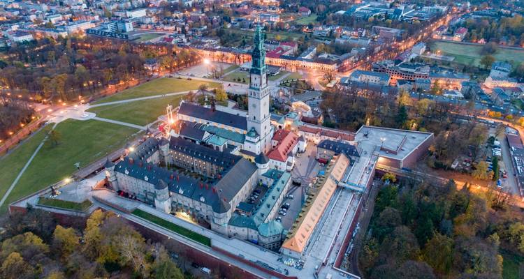 Vue aérienne en soirée du complexe du monastère de Jasna Góra illuminé parmi le feuillage automnal