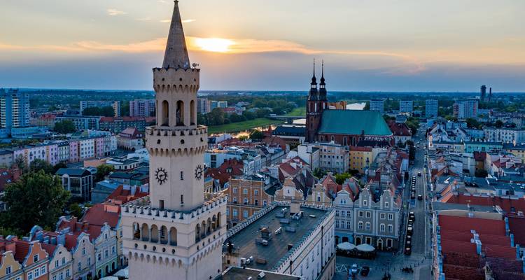Vue aérienne au crépuscule d'Opole avec la tour de l'hôtel de ville historique se découpant en silhouette contre le soleil couchant.