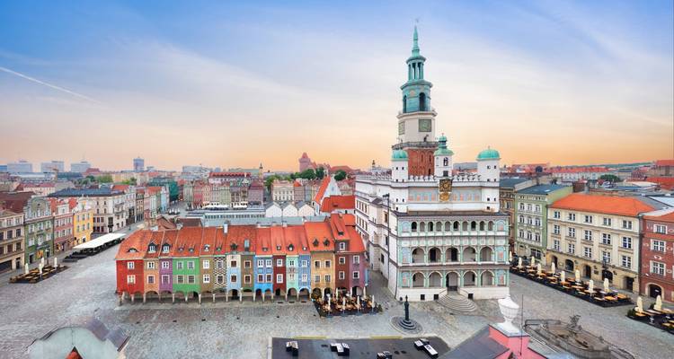 Poznan Old Market Square with colorful merchant houses and Renaissance town hall at sunrise.