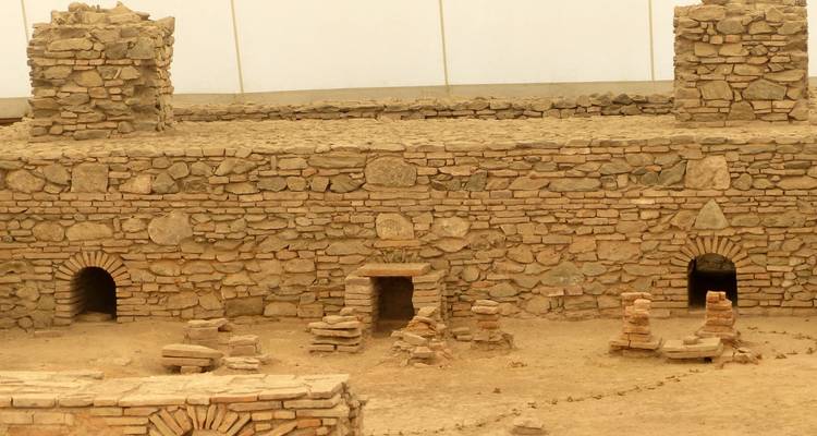 Murs de pierre romains excavés et petites portes en arche dans un site archéologique.