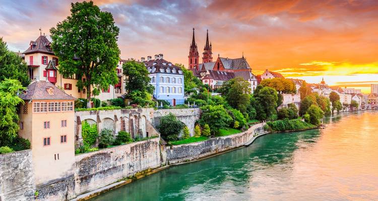Les maisons colorées au bord de la rivière et les tours de la cathédrale illuminées par un coucher de soleil éclatant au-dessus d'une rivière calme.