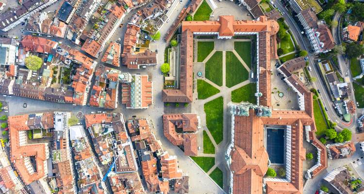 Vue aérienne du complexe abbatial historique et de la pelouse en damier entourés par les toits densément serrés de la vieille ville.