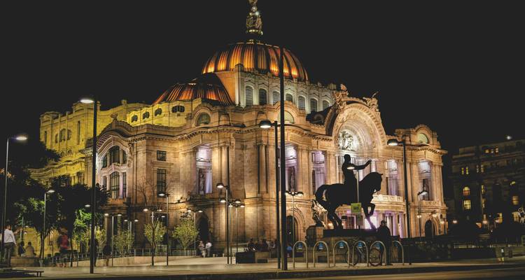Le Palacio de Bellas Artes illuminé rayonne la nuit, couronné par son dôme de cuivre et sa façade ornée.