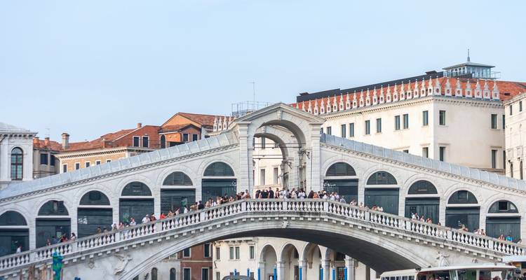 Les foules se tiennent au sommet du pont Rialto en marbre blanc de Venise enjambant le Grand Canal.