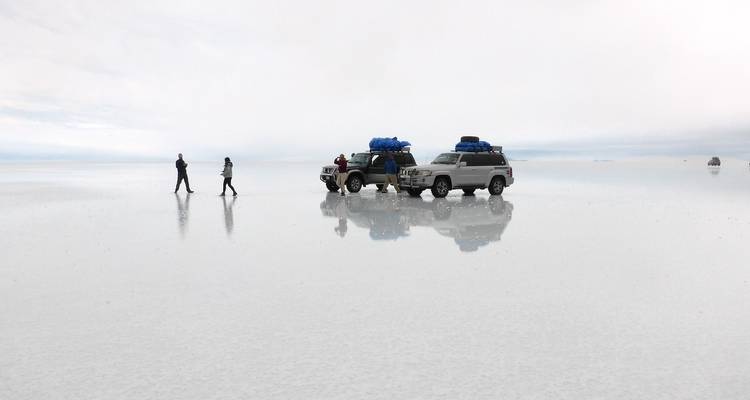 Los vehículos de tour y los viajeros crean reflejos como espejo en el Salar de Uyuni inundado.