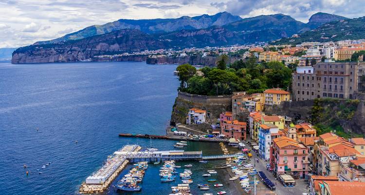 Les bâtiments colorés et les petits bateaux s'amassent le long du port en falaise de Sorrente, surplombant la mer Tyrrhénienne d'un bleu profond.
