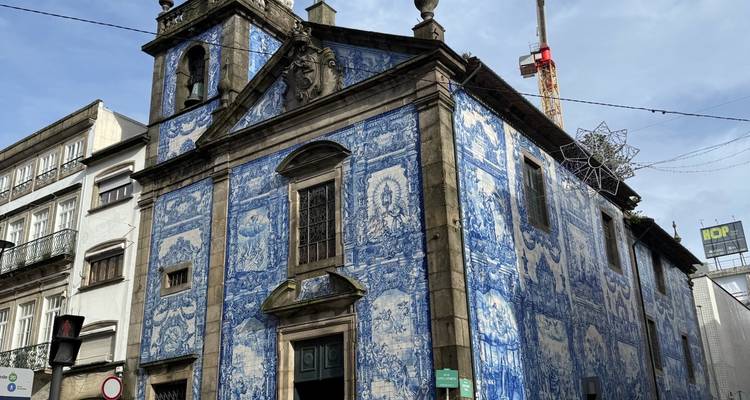 Fachada de la iglesia Capela das Almas con azulejos azules en Oporto con una grúa de construcción detrás.