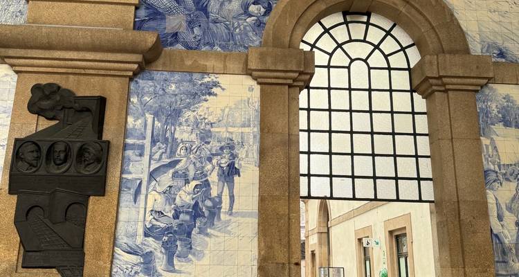 Arco interior con murales de azulejo y ventana con marco de hierro en la estación de tren de Oporto.