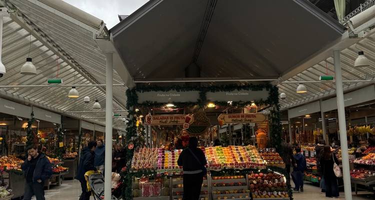 Puesto de productos frescos en el interior de una galería de mercado decorada para las fiestas, multitudes mirando las coloridas frutas en exhibición.