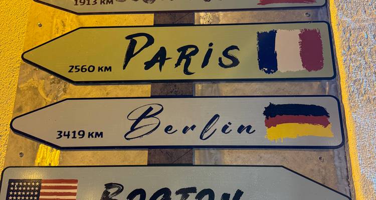 Cartel decorativo que indica distancias a París, Berlín y otras ciudades montado en una pared.