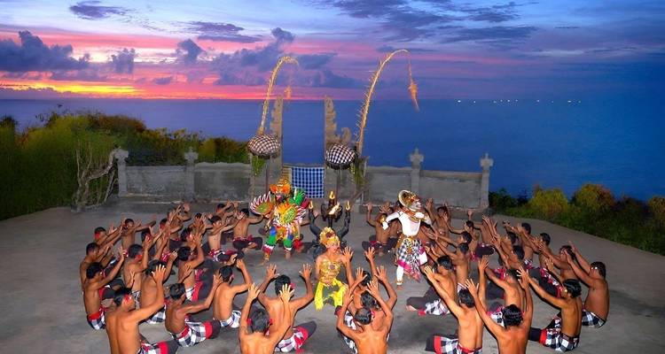Spectacle de danse Kecak au coucher du soleil sur une scène en haut d'une falaise surplombant l'océan.