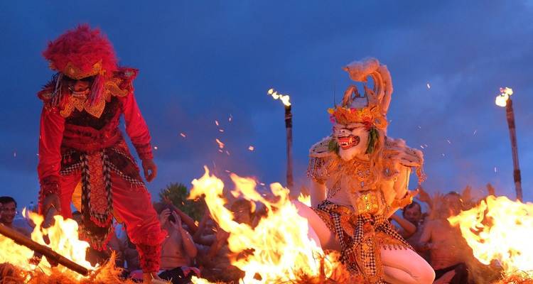 Danseurs de feu balinais traditionnels en costumes dramatiques entourés par les flammes.