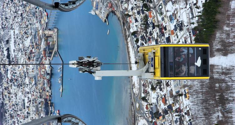 Cabine du téléphérique Yellow Fjellheisen suspendue haut au-dessus de Tromsø avec une vue aérienne panoramique de la ville et du fjord.