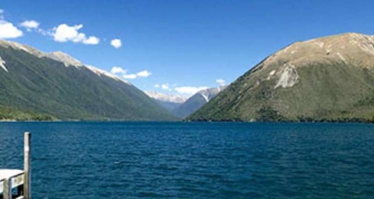 Vaste lac bleu encadré par des collines escarpées et arides sous un beau jour d'été.