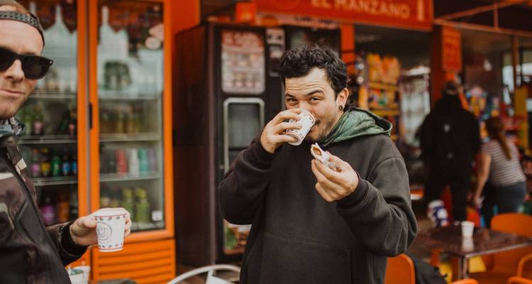 Ein Reisender genießt einen schnellen Kaffee an einem farbenfrohen kolumbianischen Straßenverkaufsstand.