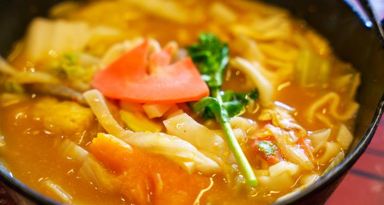Primer plano de un abundante tazón de sopa de fideos japonesa adornado con verduras.