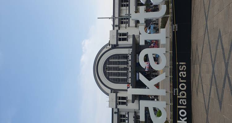 Panneau de la ville de Jakarta et entrée animée de la gare ferroviaire moderne sous un ciel bleu