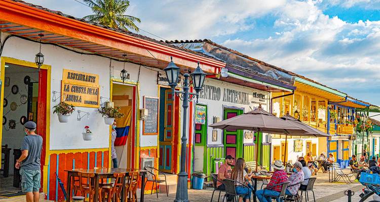Charmante Kleinstadt-Straße mit regenbogenfarbenen Gebäuden und Café-Terrassen.