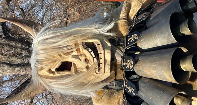 Close-up van een gerimpeld houten masker met wit, warrig haar gedragen door een Kukeri-performer.