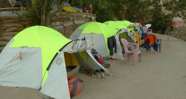 Rangée de tentes d'expédition aux couleurs de néon brillant avec équipement et vêtements en train de sécher sur un site de camp de base.