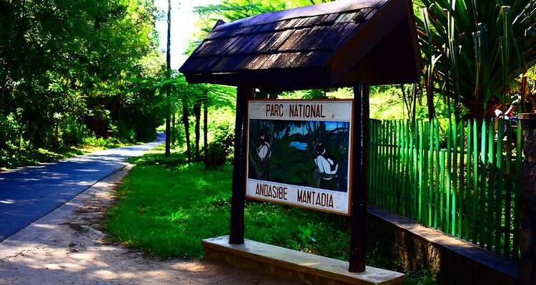 Panneau en bois au bord de la route pour le Parc National Andasibe Mantadia entouré de verdure luxuriante et d'une ruelle tranquille