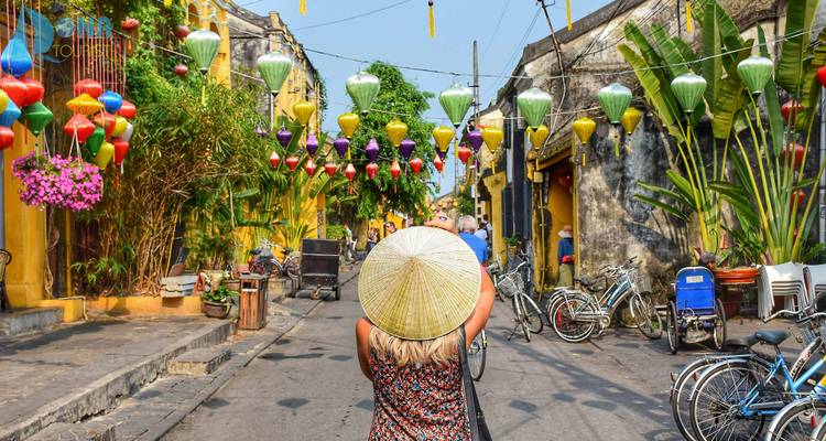 Reiziger met een punthoed loopt door een met lampionnen versierde straat in Hoi An's oude stad.