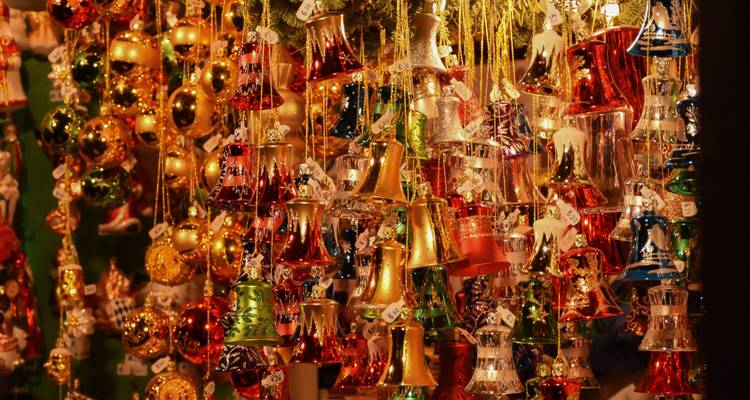 Una abundancia de brillantes adornos navideños y campanas doradas cuelgan densamente en una cálida luz festiva.