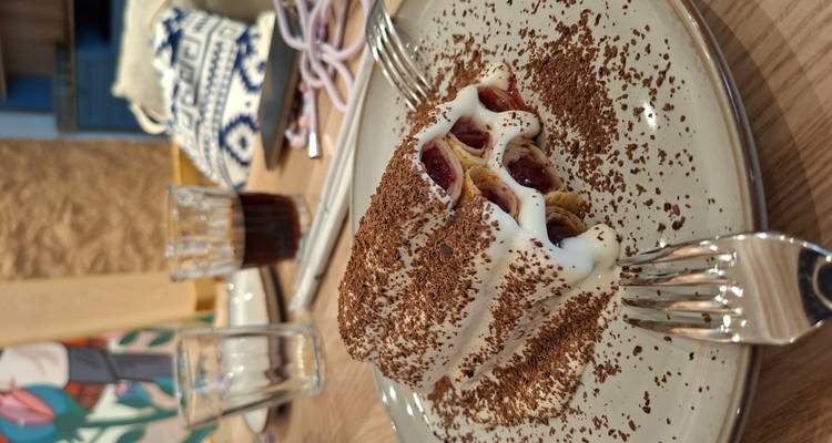 Gros plan d'un dessert dressé composé de crêpes roulées recouvertes de crème et de copeaux de chocolat.