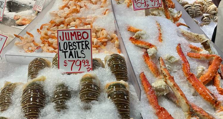 Gros plan sur les queues de homard géant et les pattes de crabe sur la glace concassée avec étiquettes de prix.