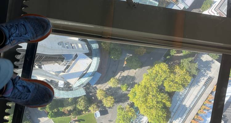 En regardant vers le bas à travers le plancher de verre de la Space Needle de Seattle, les chaussures d'un visiteur sont visibles au-dessus des immeubles de la ville et des cimes des arbres bien en dessous.