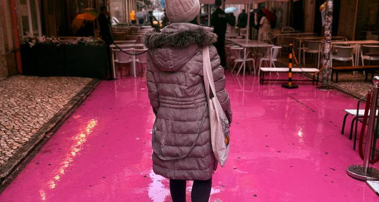 Back view of woman walking the glossy pink pavement of Lisbon’s nightlife street