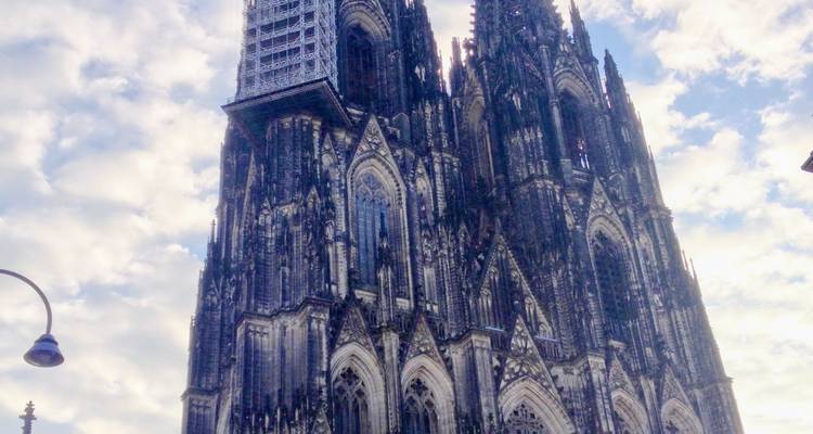 Vue diurne ascendante des tours gothiques imposantes de la Cathédrale de Cologne contre un ciel dégagé.